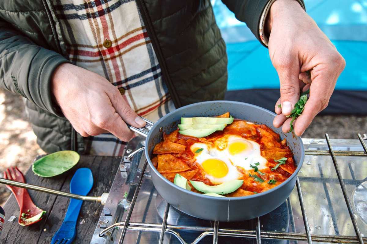 Chilaquiles ایک آسان کیمپنگ ناشتے کا آئیڈیا ہے - کرسپی ٹارٹیلس ایک مسالیدار ٹماٹر کی چٹنی میں ابال کر انڈوں کے ساتھ سب سے اوپر ہے۔ اسے بنانے میں 30 منٹ سے بھی کم وقت لگتا ہے، اور یہ