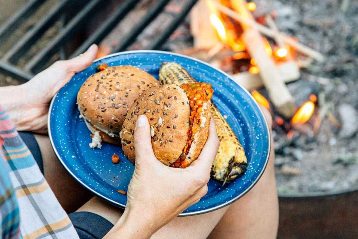 Sloppy Joes aux lentilles rouges sur une assiette de camping bleue avec un feu de camp en arrière-plan