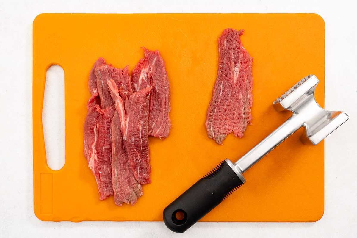 Nakrájené hovězí maso a palička na oranžovém prkénku