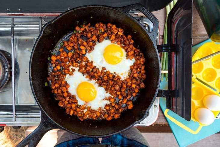 Dua butir telur dalam wajan besi cor berisi chorizo ​​​​dan ubi jalar