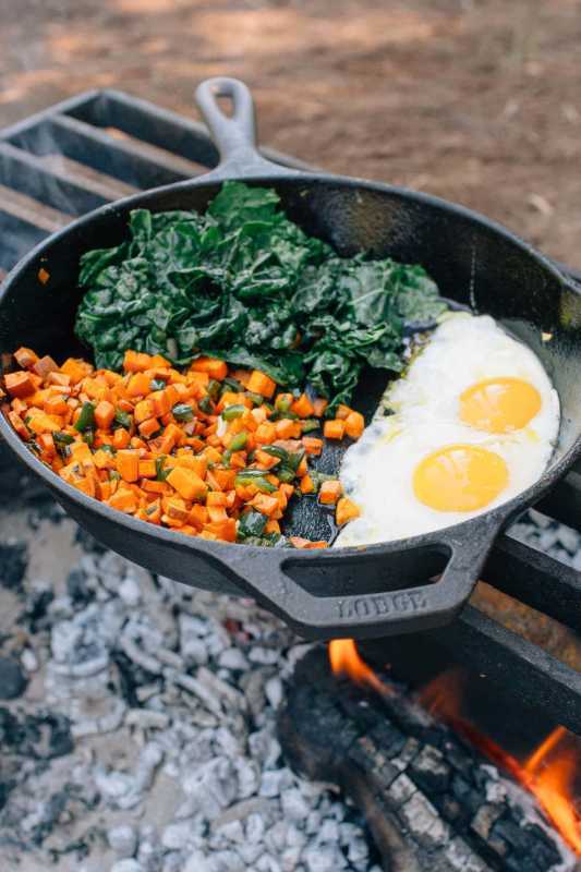 Hash śniadaniowy i jajka na żeliwnej patelni nad ogniskiem