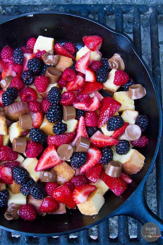 Een koekenpan gevuld met vierkante cakejes, aardbeien, frambozen en bramen
