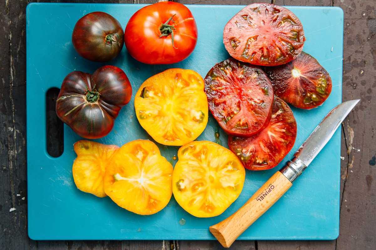 Червени и жълти реликви домати на синя дъска за рязане
