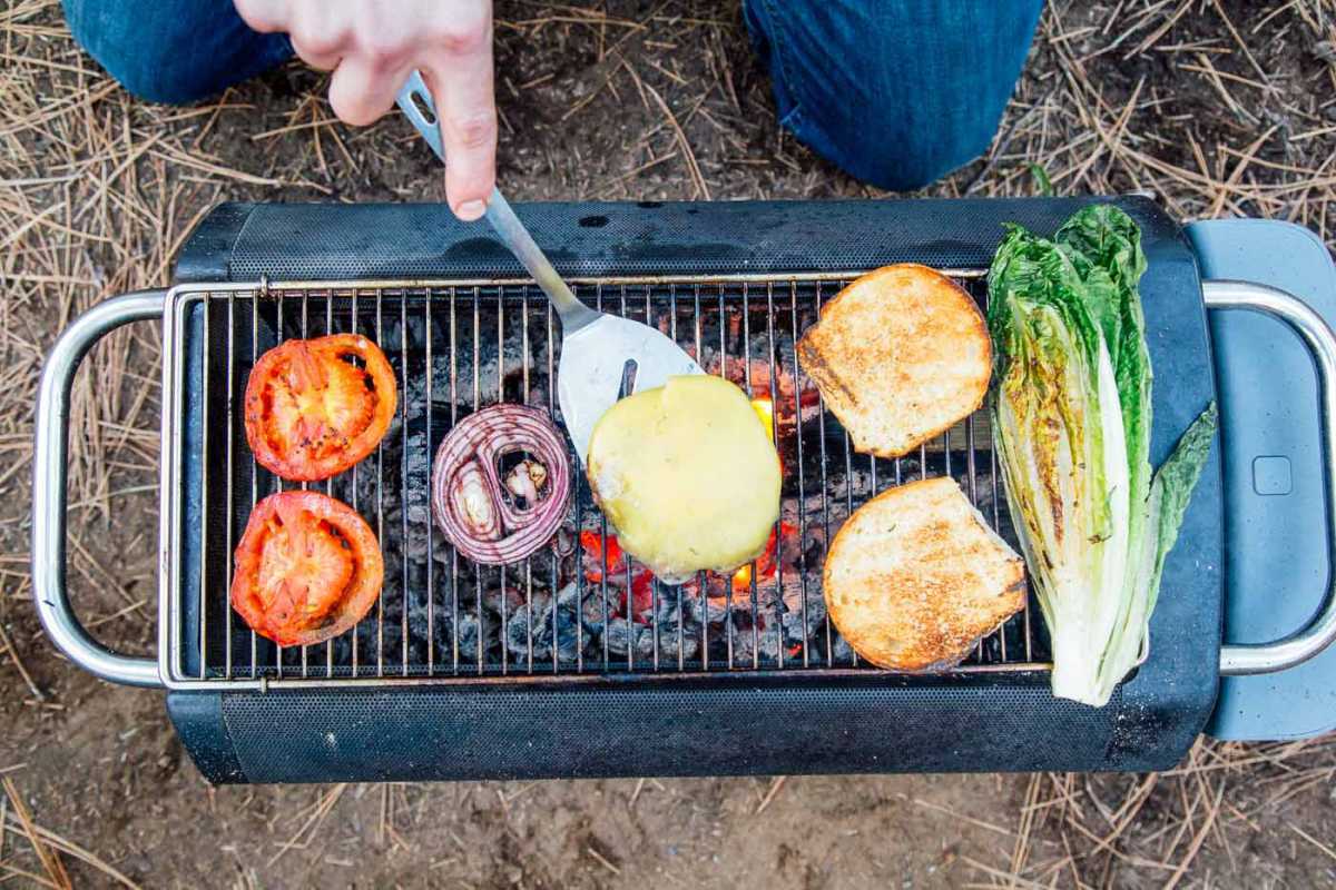 Oversikt over tomater, løk og burgere på en grill