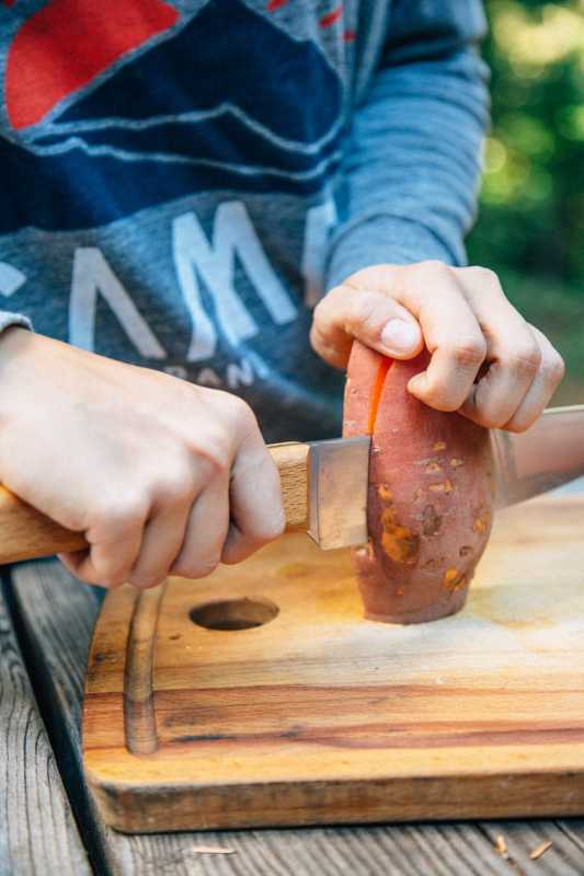 Меган реже сладки картофи на дървена дъска за рязане