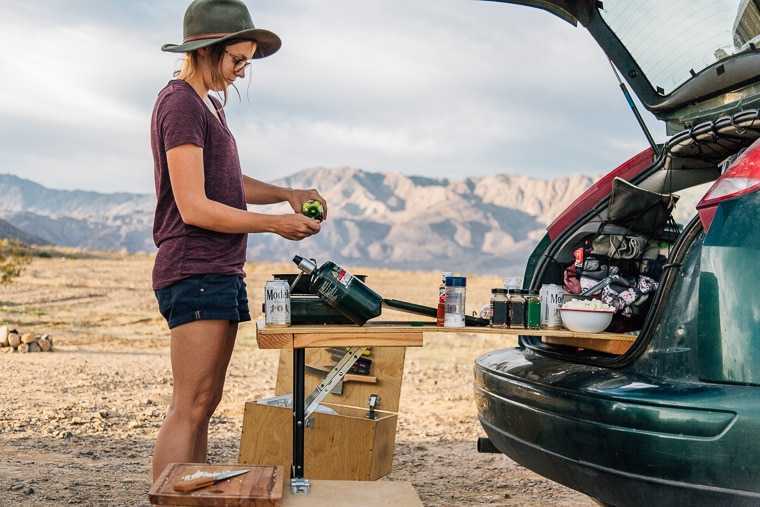 Megan gamina maistą ant stovyklavietės viryklės, kuri yra ant automobilio bagažinės