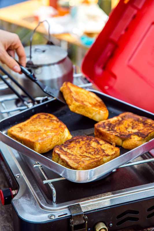 Vier Scheiben French Toast in einer quadratischen Pfanne auf einem Campingkocher