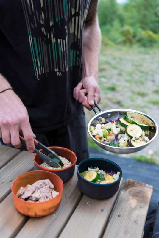 Saltee los fideos y la carne de res en un tazón verde para acampar