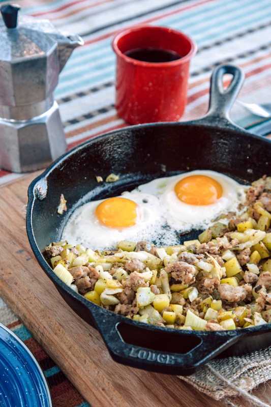 Λουκάνικο και μάραθο χασίς με δύο αυγά σε μαντεμένιο τηγάνι Δίπλα σε ένα φλιτζάνι καφέ