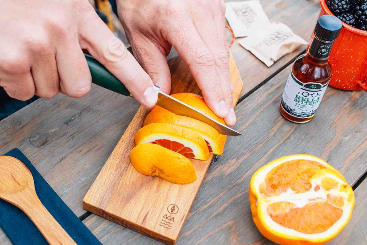 Michael cortando una naranja sobre una pequeña tabla de cortar de madera
