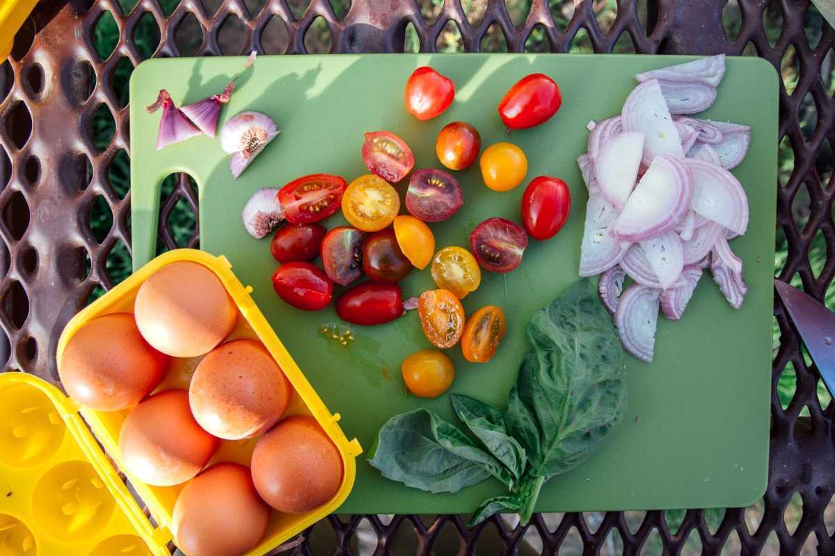 フリッタータの材料：卵、トマト、エシャロット、ニンニク、バジルをまな板の上に並べます。