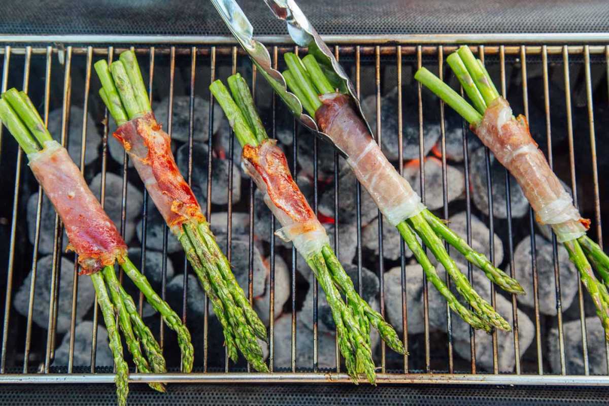 Binalot ng Prosciutto ang mga bundle ng asparagus sa isang grill
